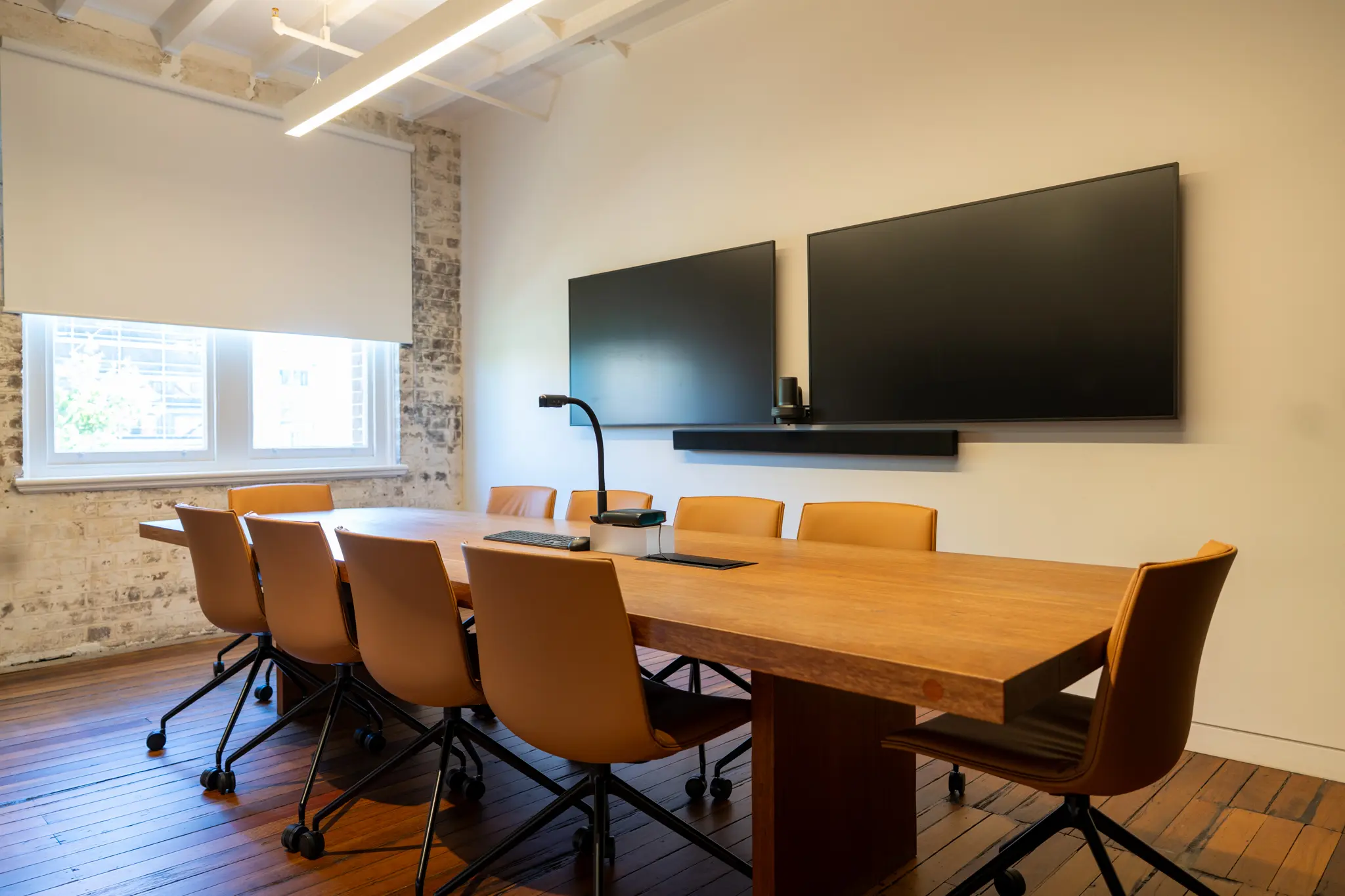 Newly refurbished office room with a large table and chairs and a television hanging on the wal