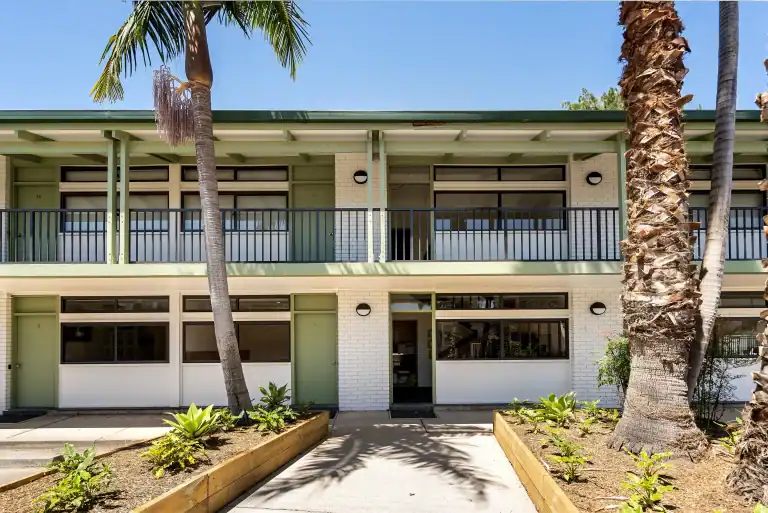 Outdoor photo of the Crown on McCredie Motel, front on with palm trees in front