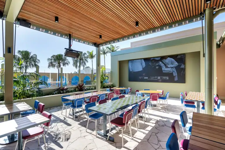 Outdoor dining area of Corrimal Hotel, with table and chairs and large television screen on the outdoor wall