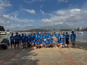 Team photo of the Fugen team in blue t shirts at the beach after completing the Cole Classic Ocean Swim race